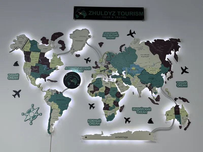 Карта мира в зелёной гамме под вывеской туристической компании Zhuldyz Tourism